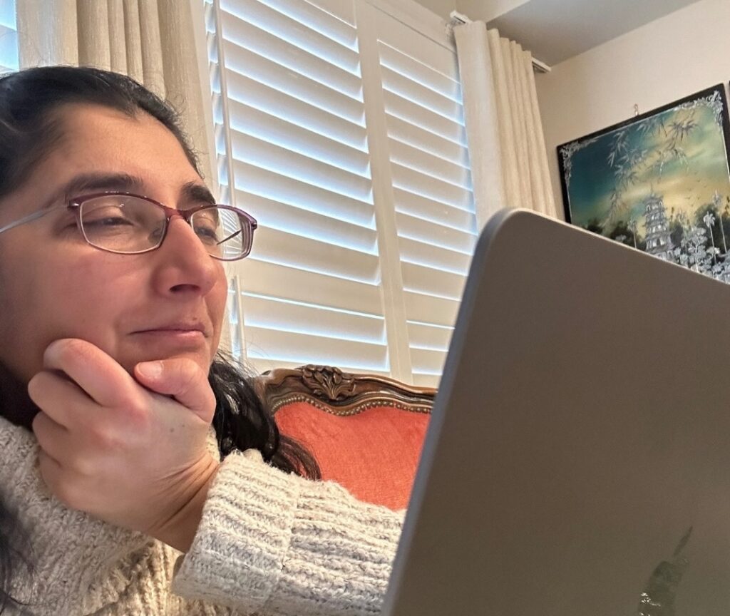 Woman sitting on a couch looking at a computer during a video-based assessment session