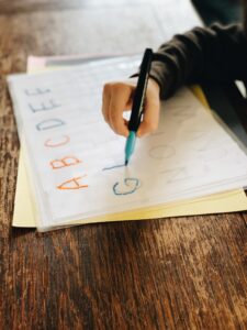 Childs hand practicing handwriting letters by tracing.