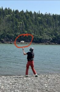 Child joyfully throwing a heavy rock into the water, showing natural sensory play.