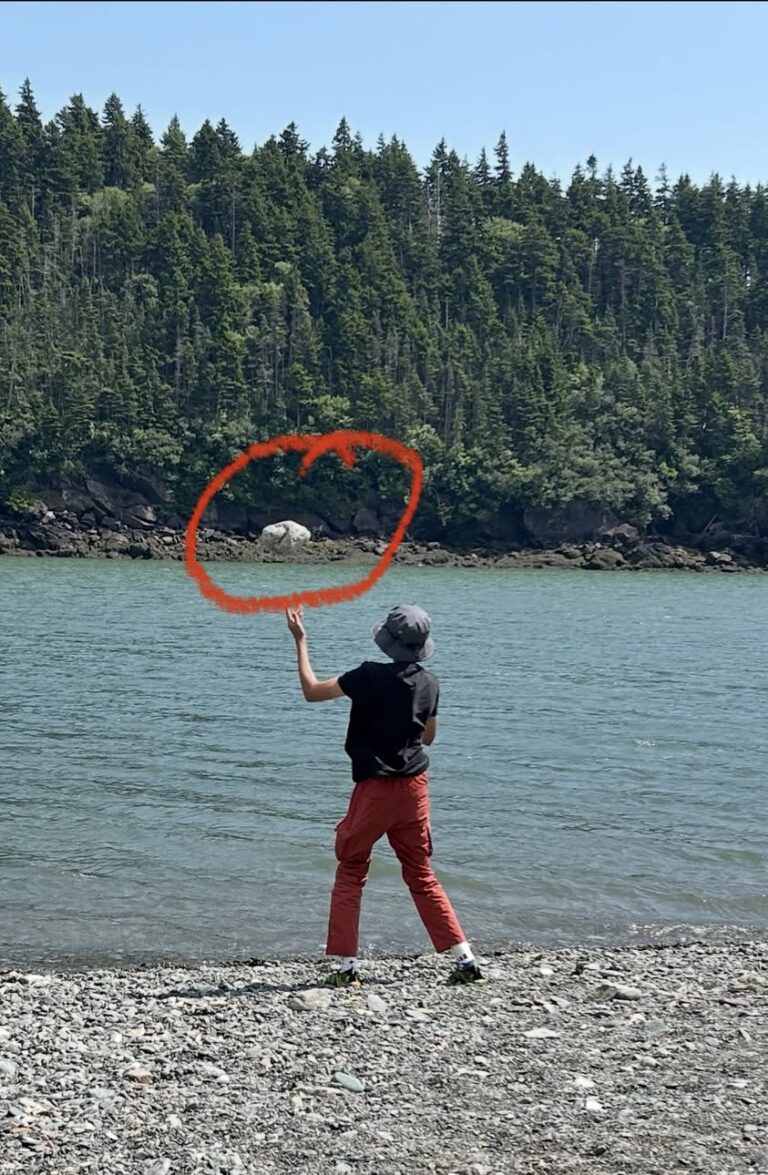 Child joyfully throwing a heavy rock into the water, showing natural sensory play.