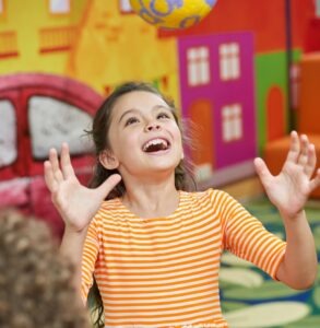 Girl smiling while throwing a ball—sensory input more or less example