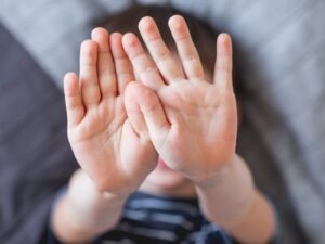 Hands held up to camera, covering face.