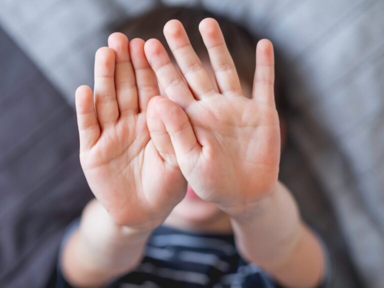 Hands held up to camera, covering face.